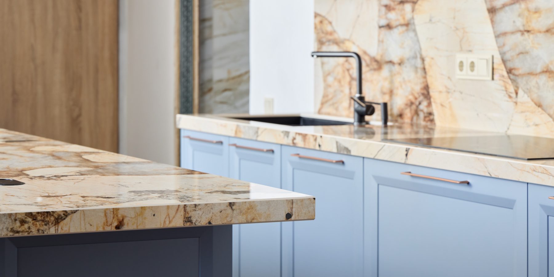A beautifully stylish kitchen featuring eyecatching, vibrant blue cabinetry along with stunning marble countertops