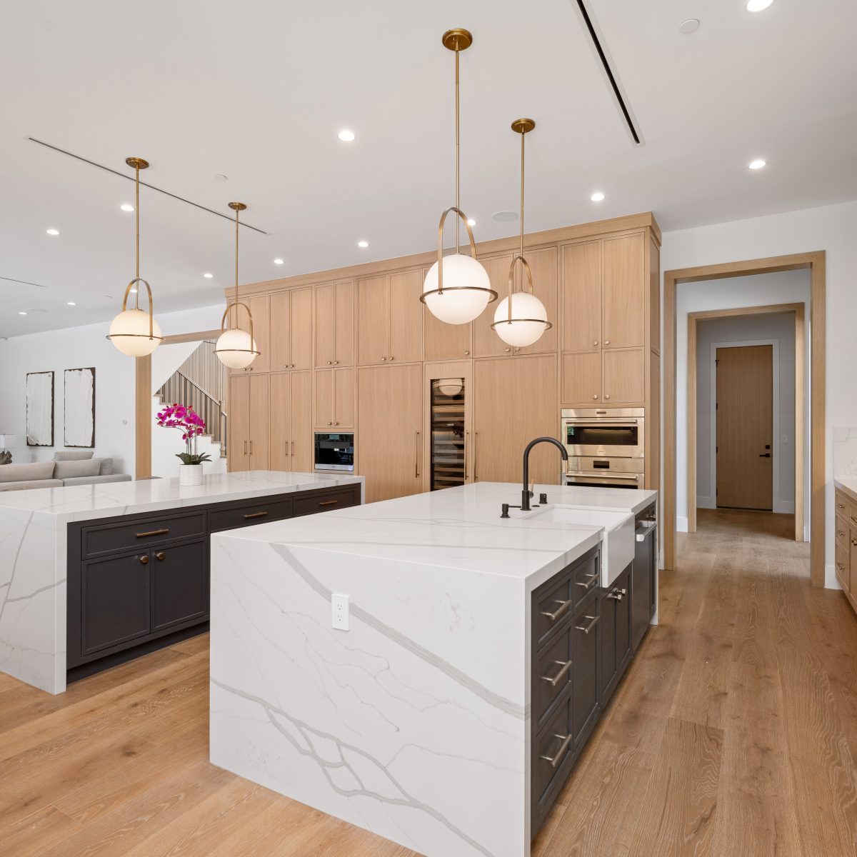 Modern kitchen with two islands, pendant lights, and wooden cabinetry in a spacious open-concept home.