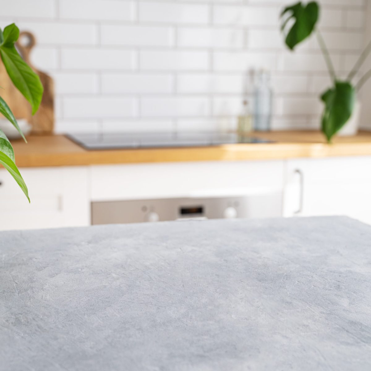 Wooden blue table top with flower pot against blurred white kitchen with cutting board in scandinavian style in morning light.